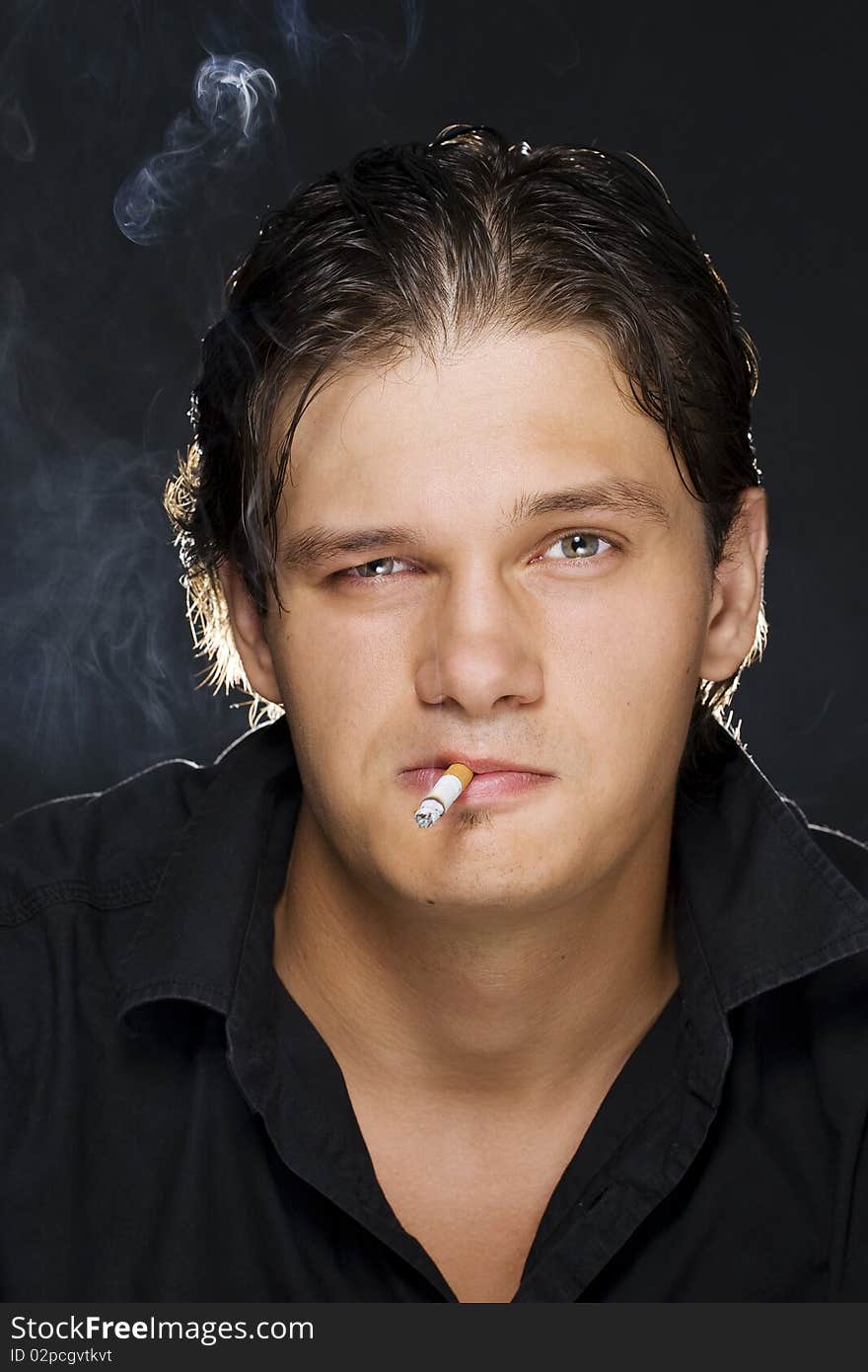 A portrait of a young man smoking a cigarette