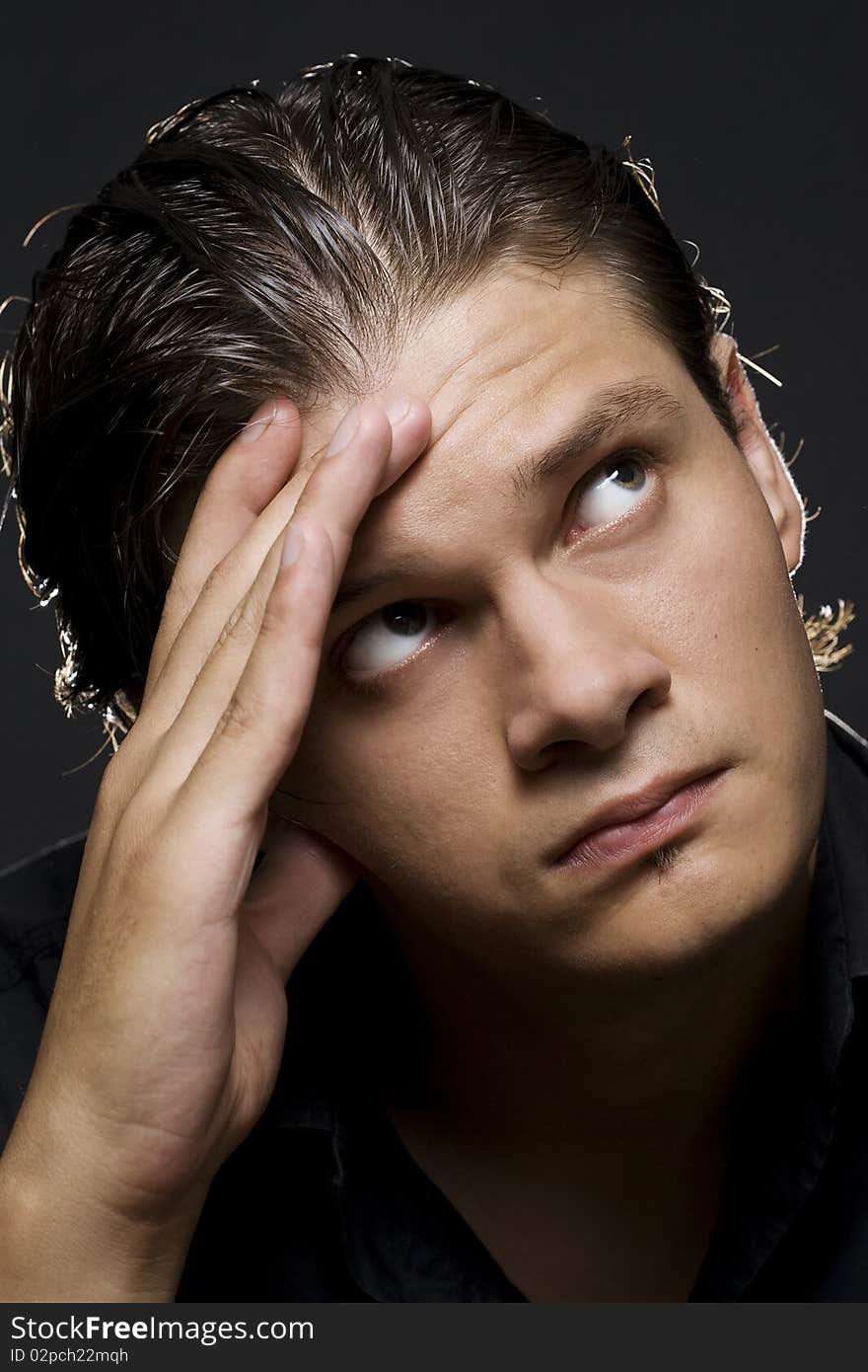 Closeup portrait of a upset young man with hand on his head