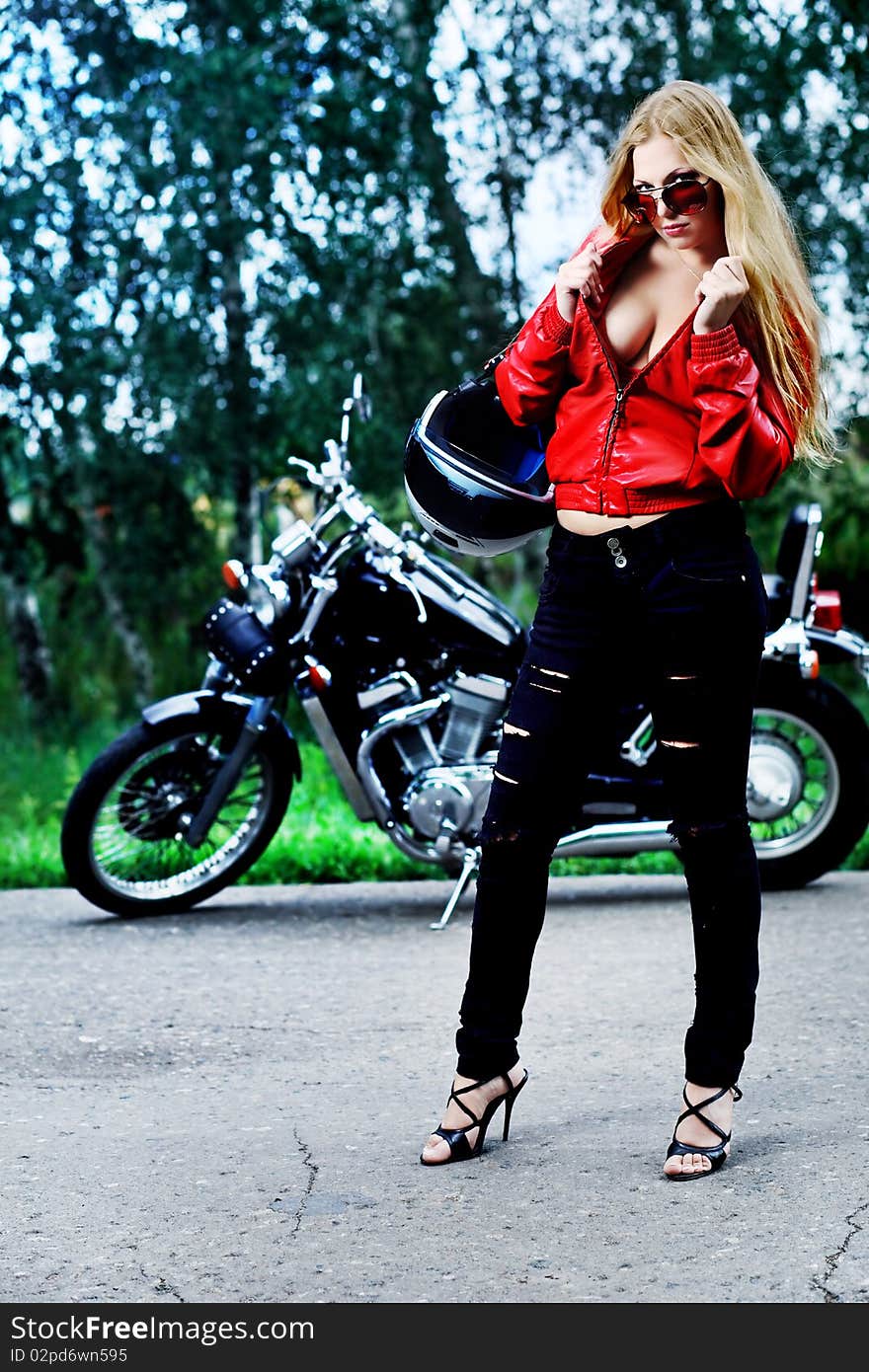 Shot of an attractive woman biker posing near her motorcycle. Shot of an attractive woman biker posing near her motorcycle.