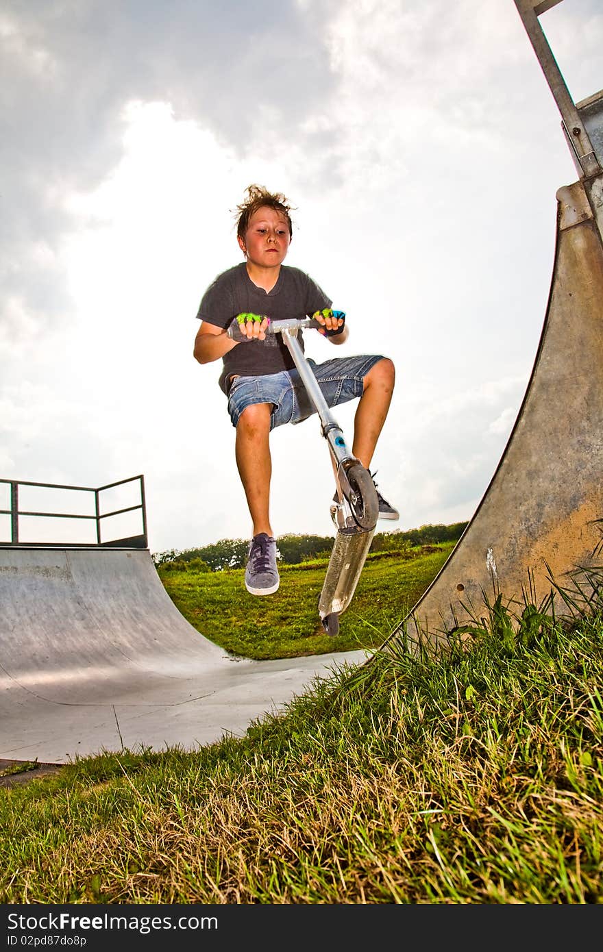 Child with scooter in  halfpipe