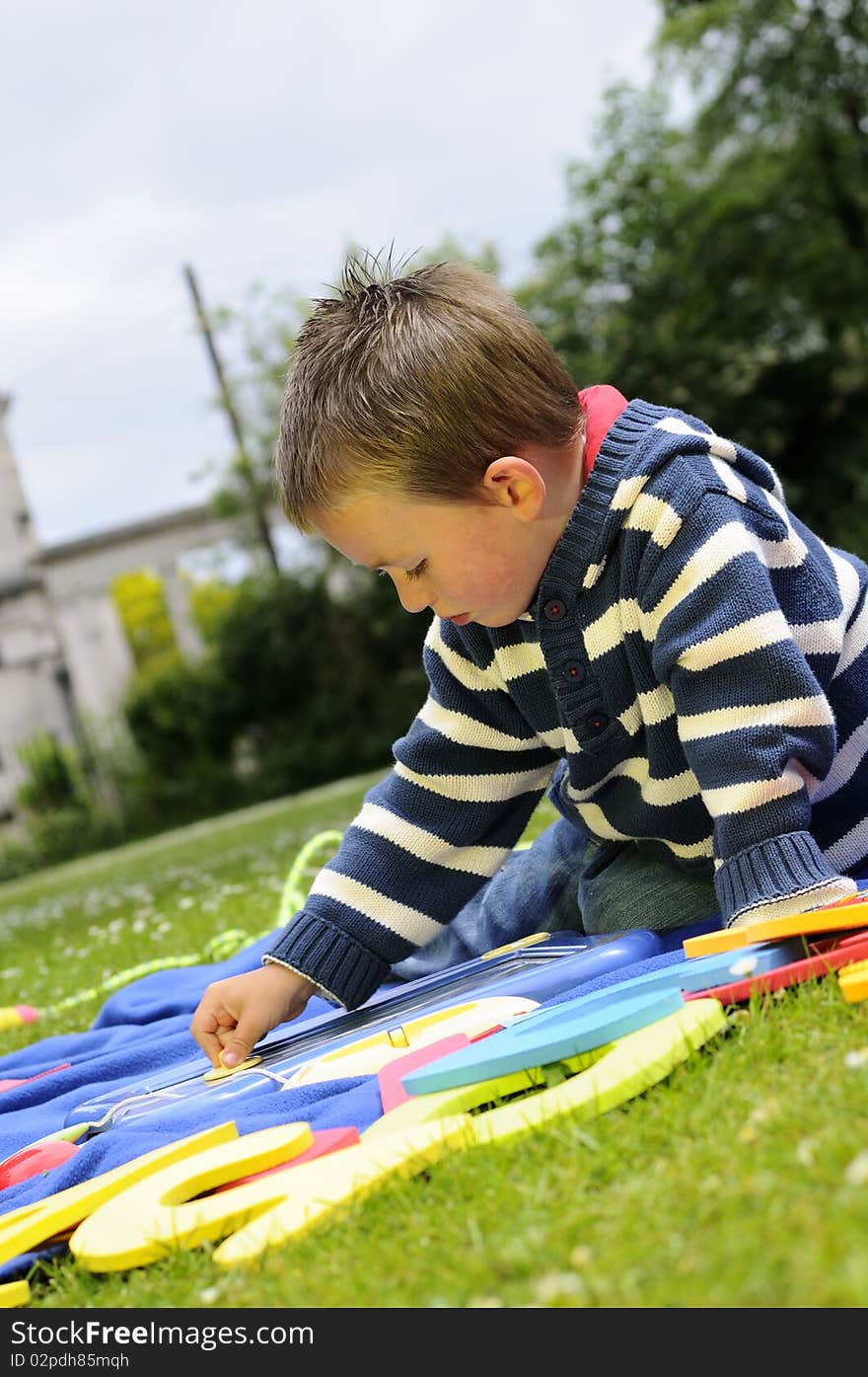 White boy studying alphabet in park