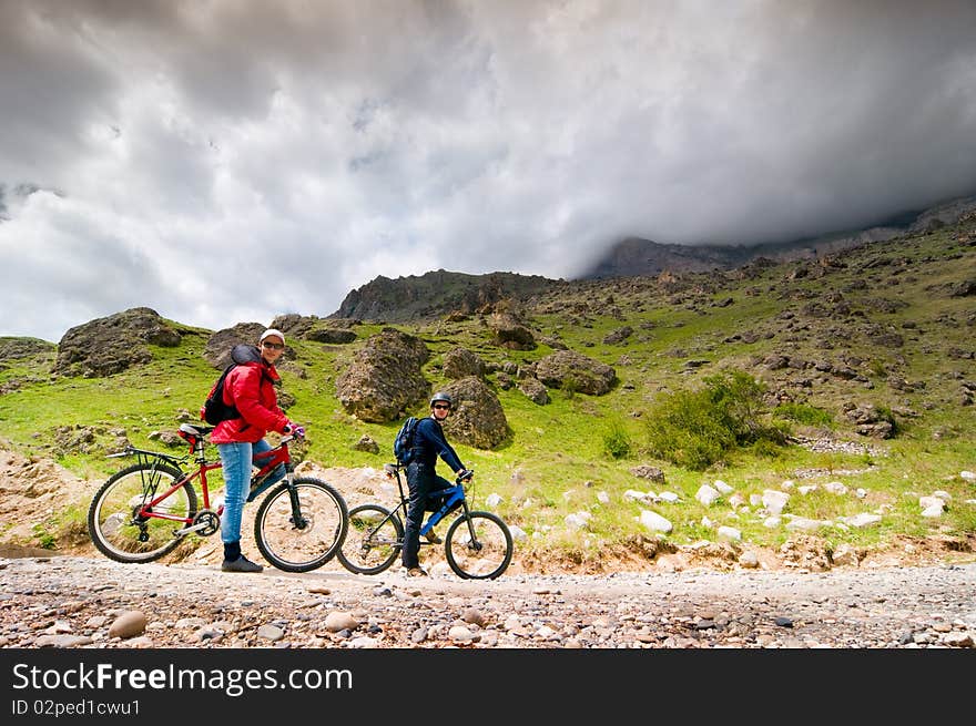 Two cyclists biking in mountains