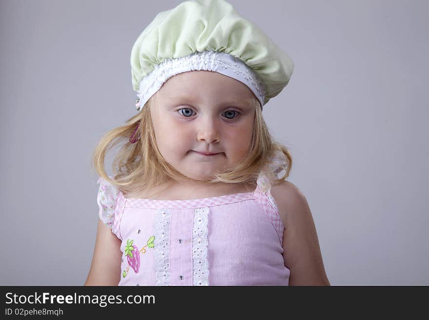 Blonde little girl looking innocent with a green hat