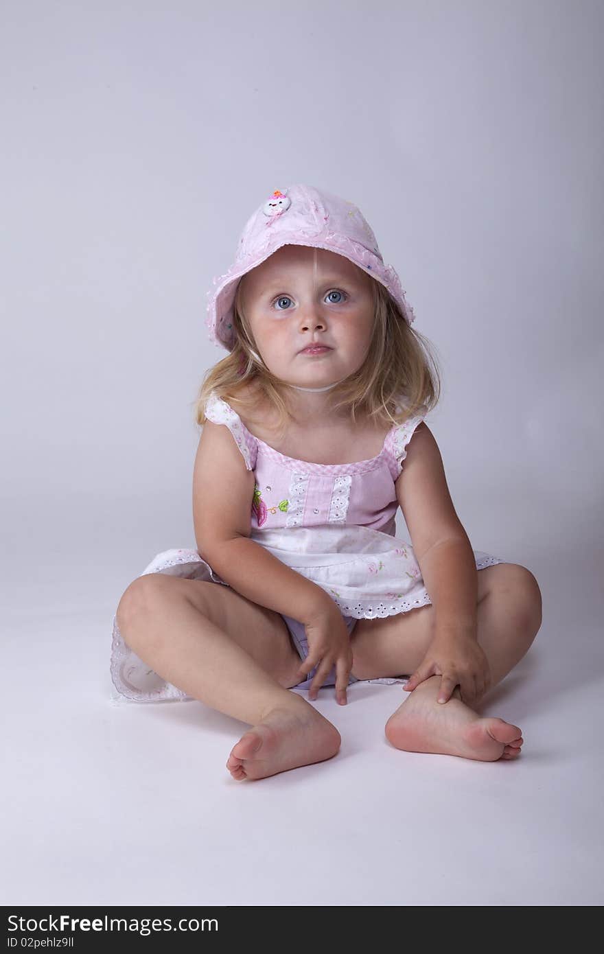 Bored little girl in pink dress wearing a hat. Bored little girl in pink dress wearing a hat