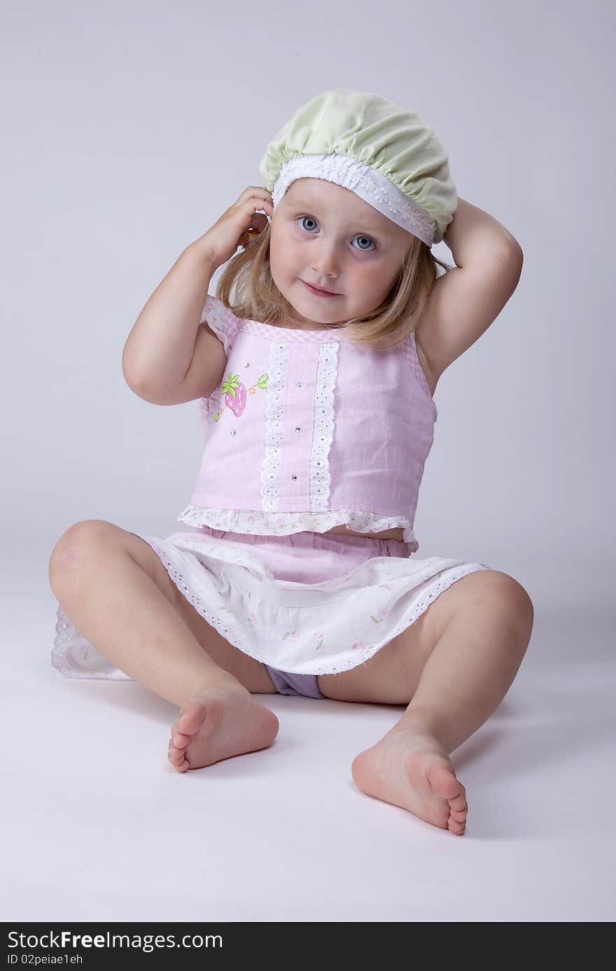 Little girl in pink dress fixing his cute green hat. Little girl in pink dress fixing his cute green hat