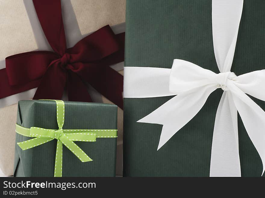 Three presents in front of each other in three different sizes.  Two are wrapped in green paper and the other is wrapped in beige. Three presents in front of each other in three different sizes.  Two are wrapped in green paper and the other is wrapped in beige.