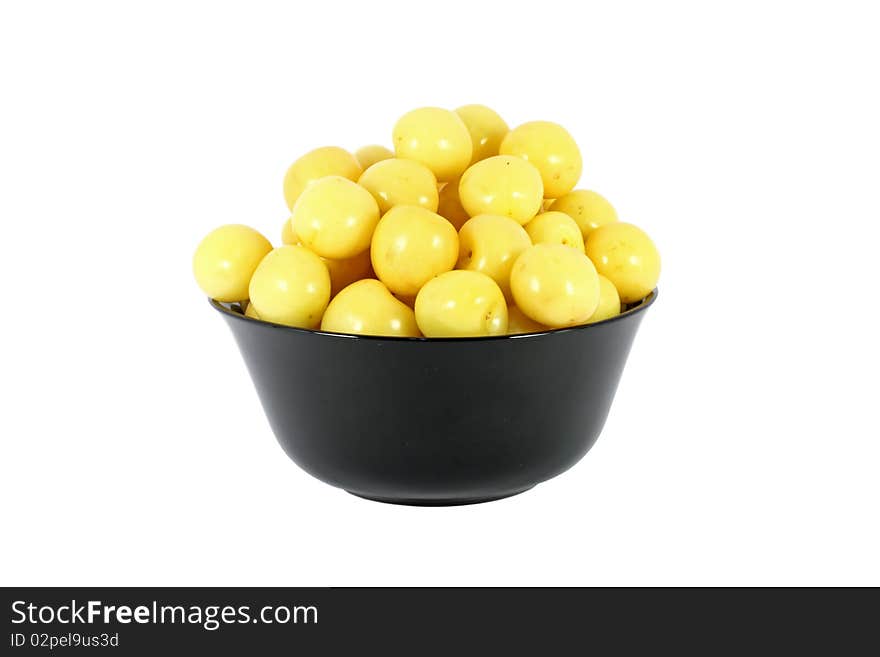 Black bowl full of yellow cherries isolated on white