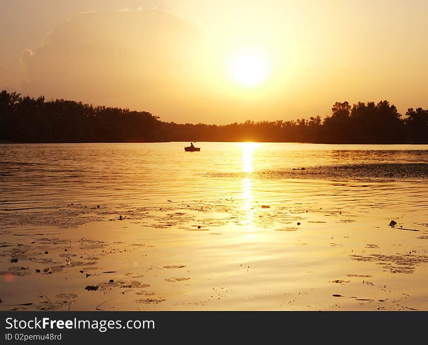 Silhouette of a fisherman on the river at sunset