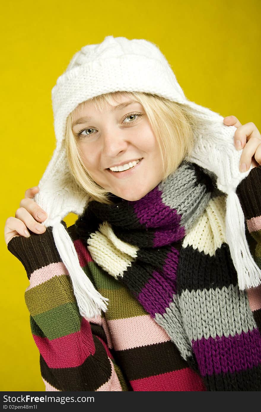 A young woman in a knitted scarf, scarf and sweater. On a yellow background. A young woman in a knitted scarf, scarf and sweater. On a yellow background