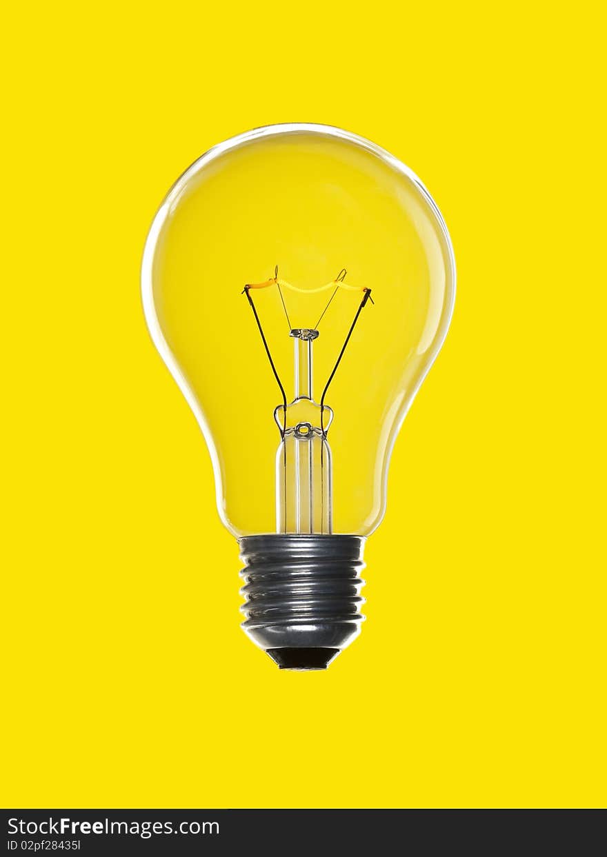 A light bulb over a yellow background. Tungsten glowing filament. A light bulb over a yellow background. Tungsten glowing filament.