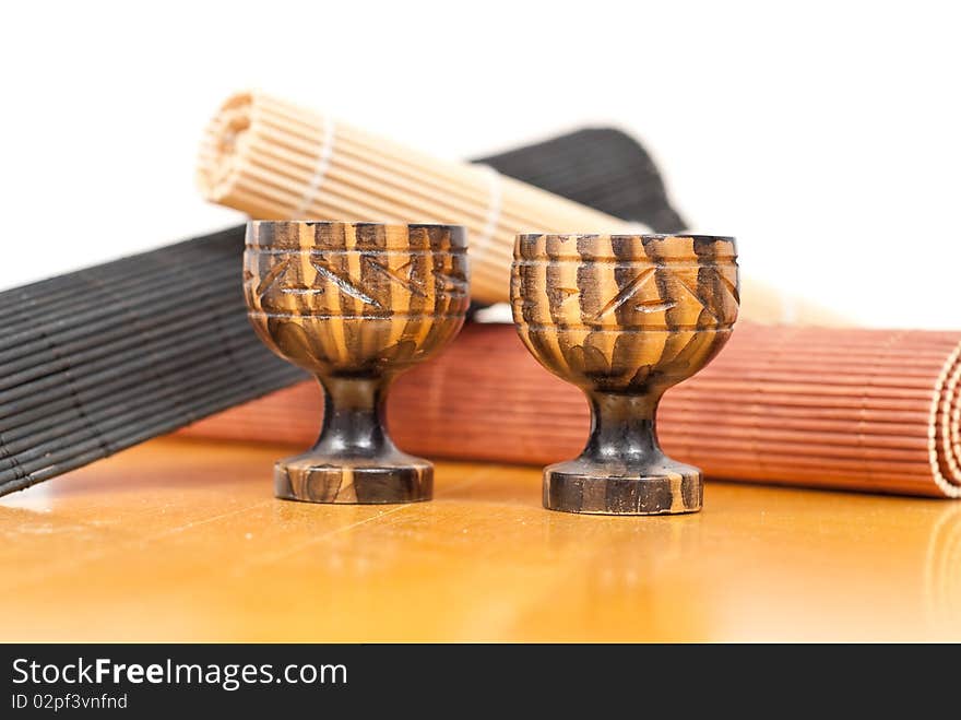 Two Mini Saki Tea Cups In Front Of Bamboo Mat Rolls. Two Mini Saki Tea Cups In Front Of Bamboo Mat Rolls