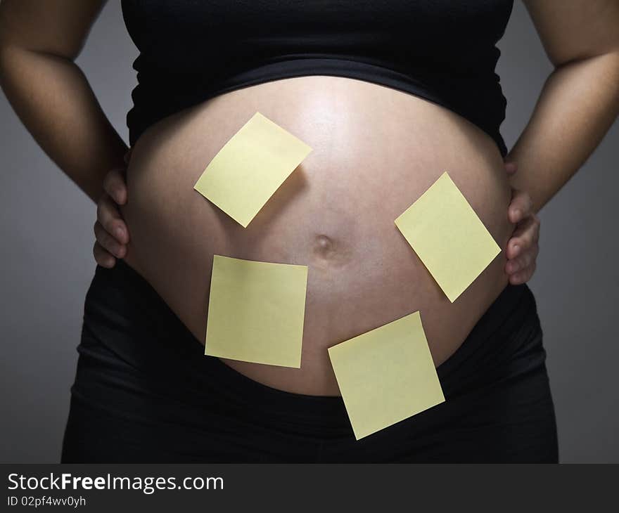 Pregnant woman with blank sticky notes on her belly. Pregnant woman with blank sticky notes on her belly.