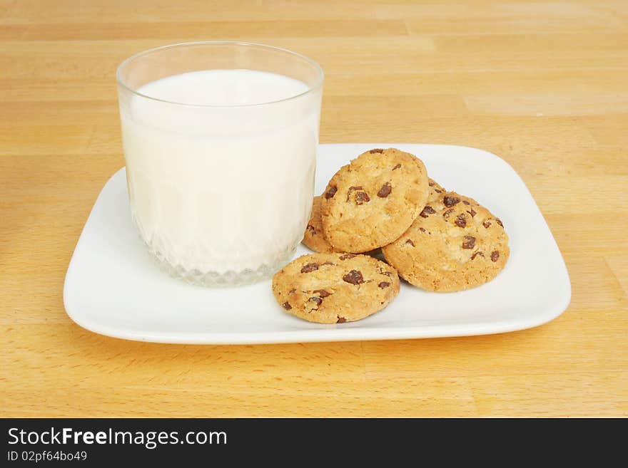 Glass of milk and chocolate chip cookies on a wooden worktop