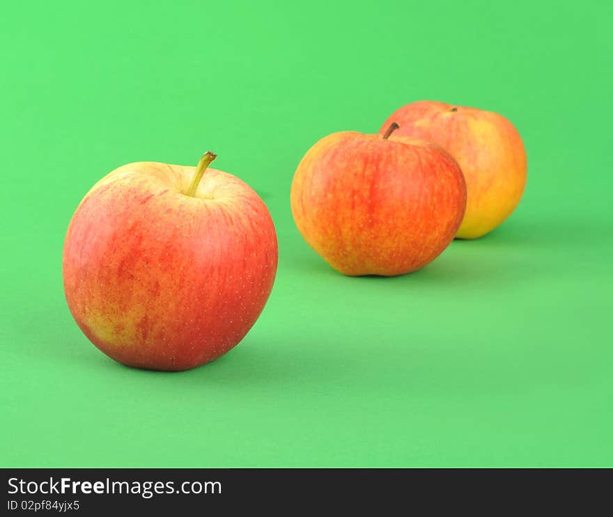 Three ripe by apples isolated over green background