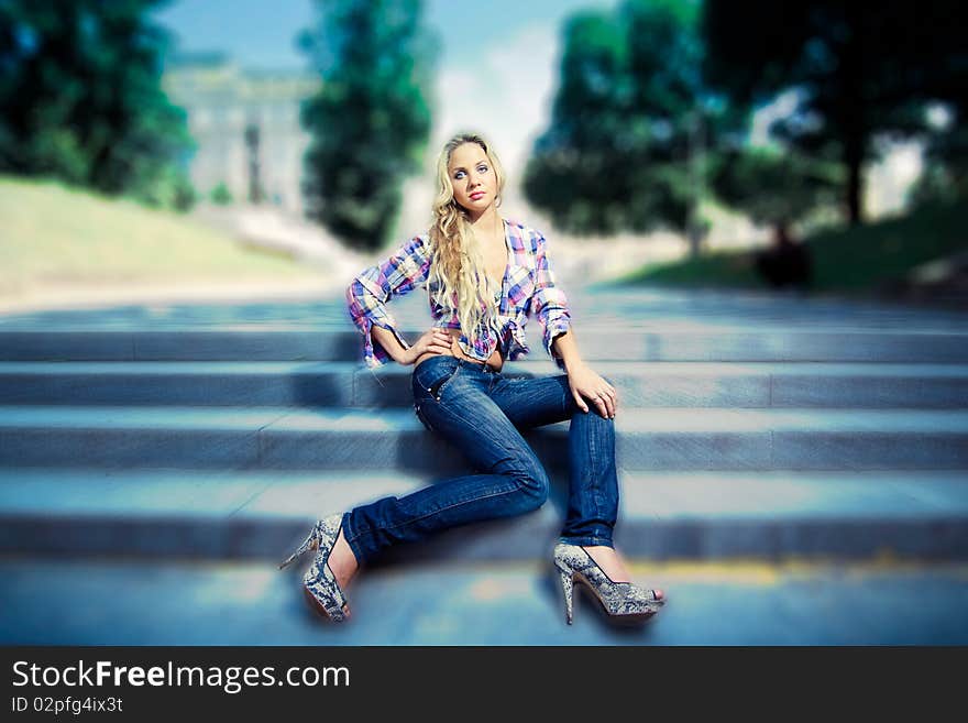 Blonde Young Woman Sitting On Stairs In The Park