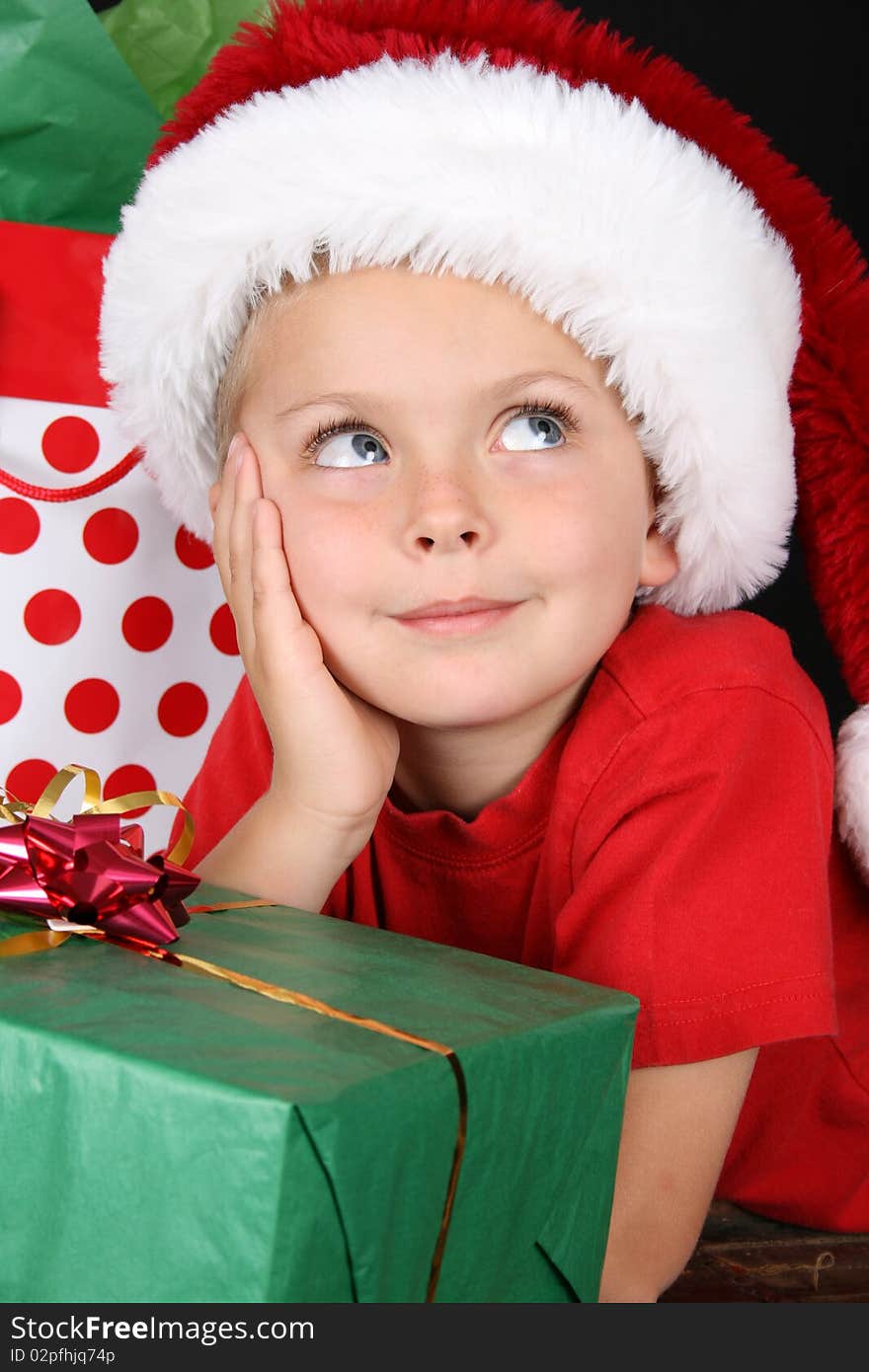 Cute caucasian boy wearing a christmas hat looking up. Cute caucasian boy wearing a christmas hat looking up