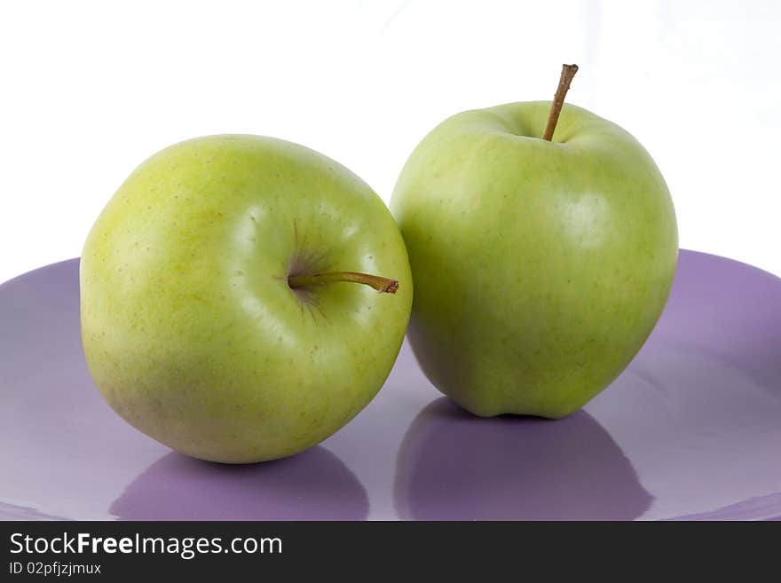 Fresh green apples on the purple plate