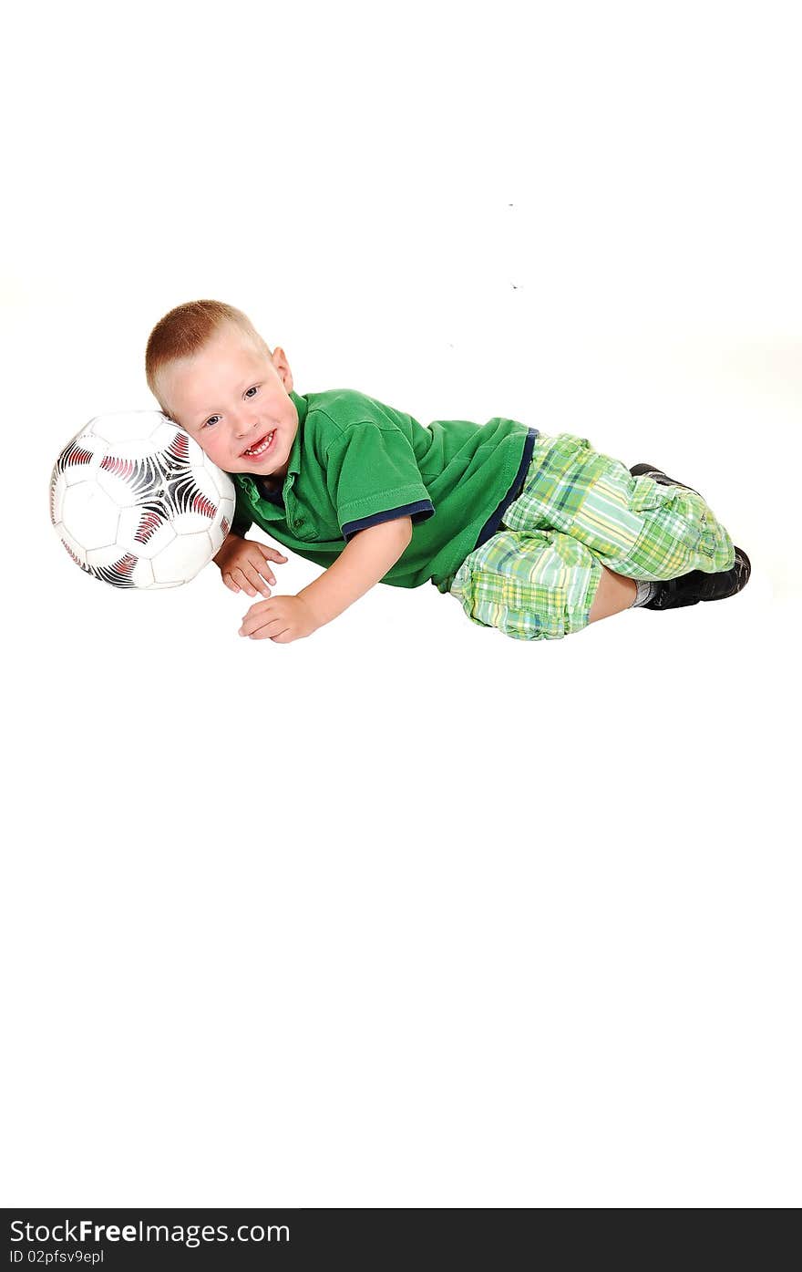 A toddler boy lying on a football in his green outfit, looking into the camera on white background. A toddler boy lying on a football in his green outfit, looking into the camera on white background.