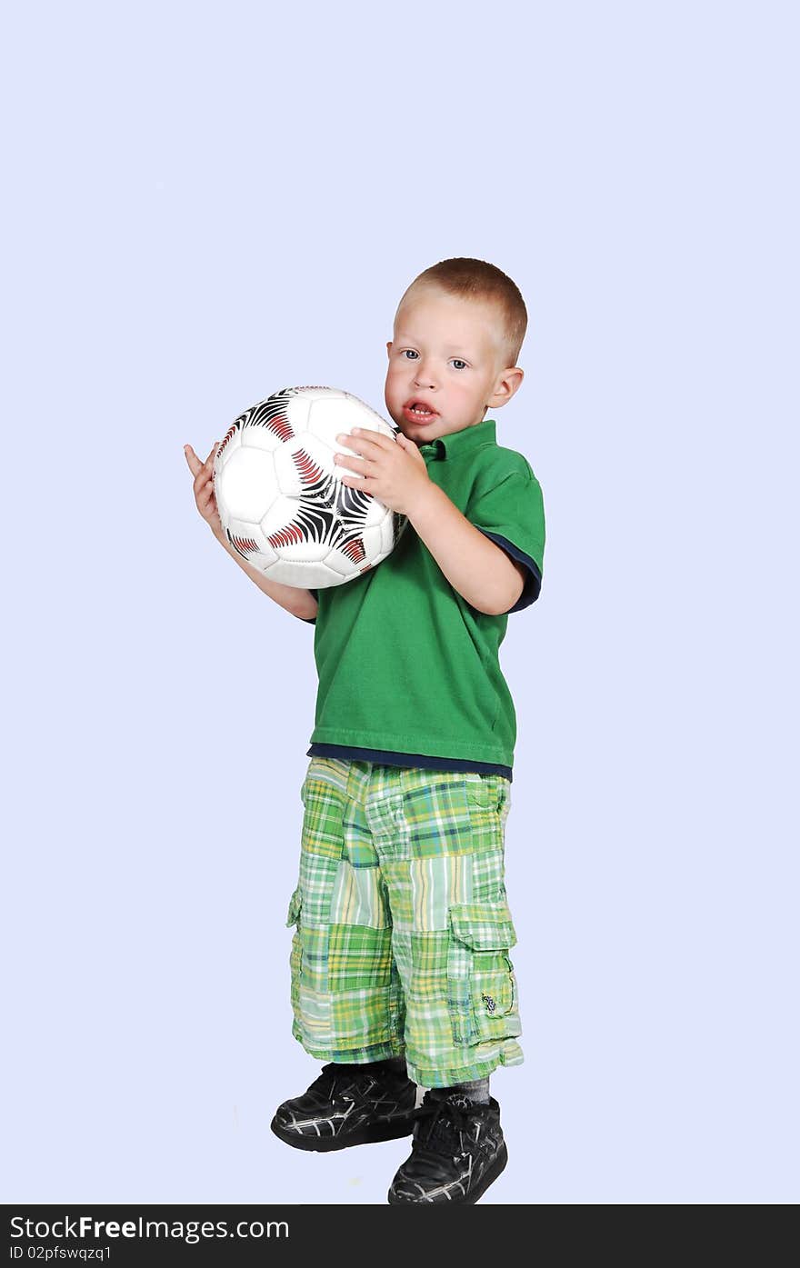 A lovely toddler standing on the floor in the studio holding up a big
soccer ball, on white background. A lovely toddler standing on the floor in the studio holding up a big
soccer ball, on white background.