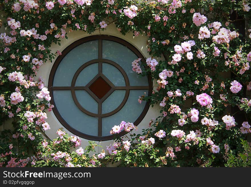 Unique round window surrounded by pink flowers. Unique round window surrounded by pink flowers.