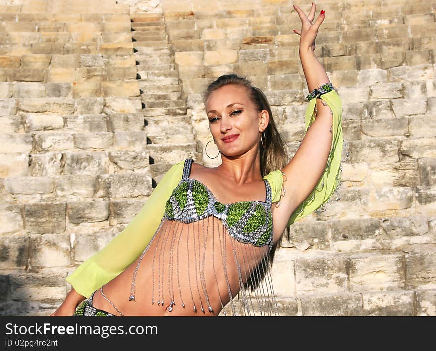 Beautiful belly dancer in green on the ancient stairs of Kourion amphitheatre in Cyprus.