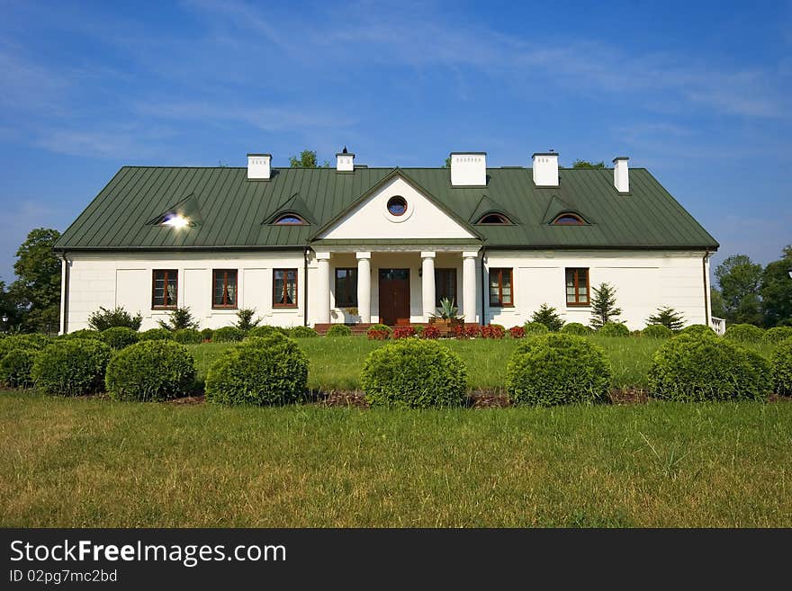 Country small manor house with the garden with the blue sky