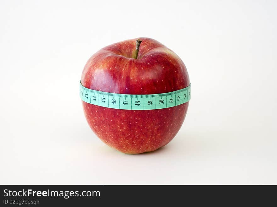 Fresh red apple wrapped up with the tape measure on the white background