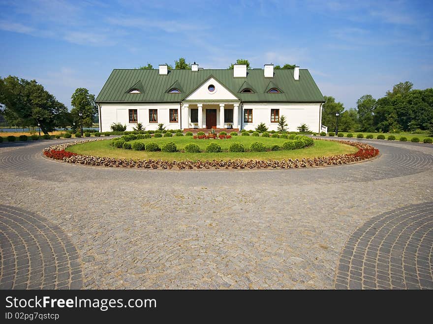 Country small manor house with the garden with the blue sky