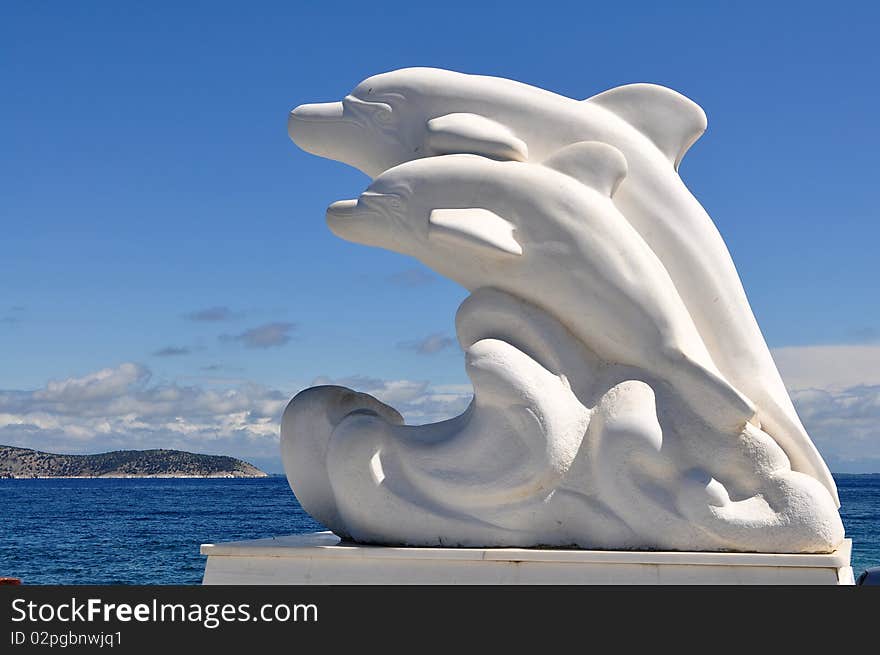 Marble dolphins in port of town Limenas((Thasos) on homonymic island.Greece,Europe.