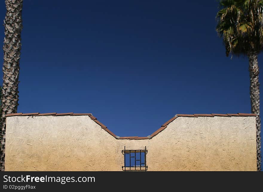 Top of building framed by two palm trees with lots of blue sky copy space. Top of building framed by two palm trees with lots of blue sky copy space