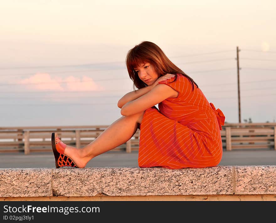 thoughtful girl in the red at sunset on the shore; warm lighting setup. thoughtful girl in the red at sunset on the shore; warm lighting setup