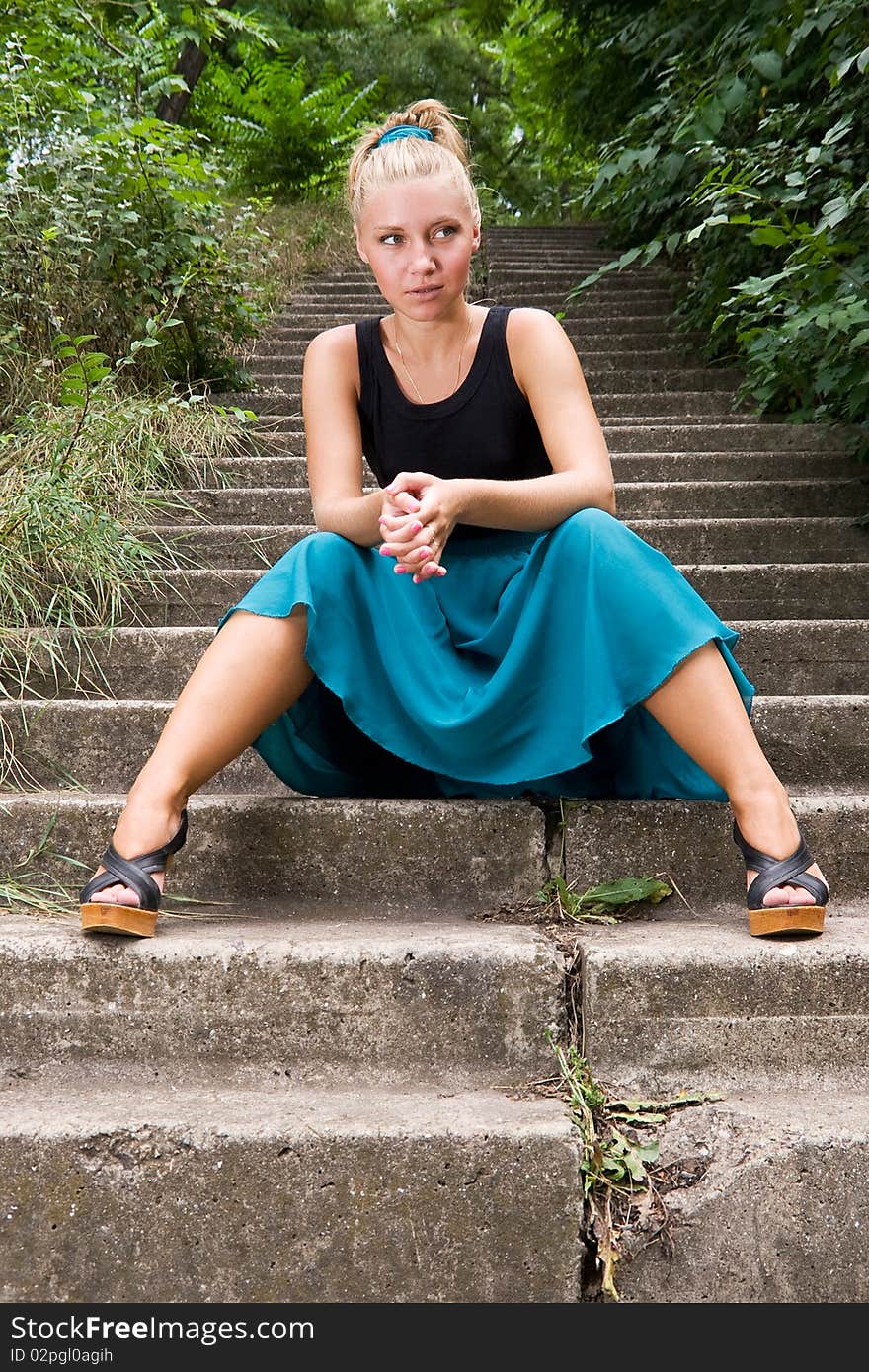 Beautiful young lady sitting on old staircase somewhere in green park. Beautiful young lady sitting on old staircase somewhere in green park