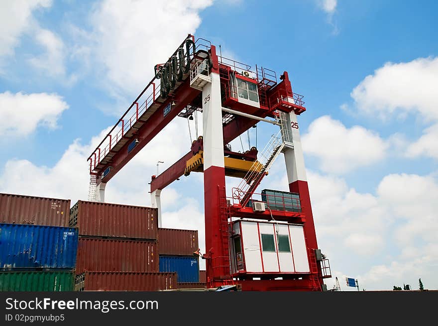 Rows of shipping containers, with a large crane overhead, lifting more containers into place. Rows of shipping containers, with a large crane overhead, lifting more containers into place