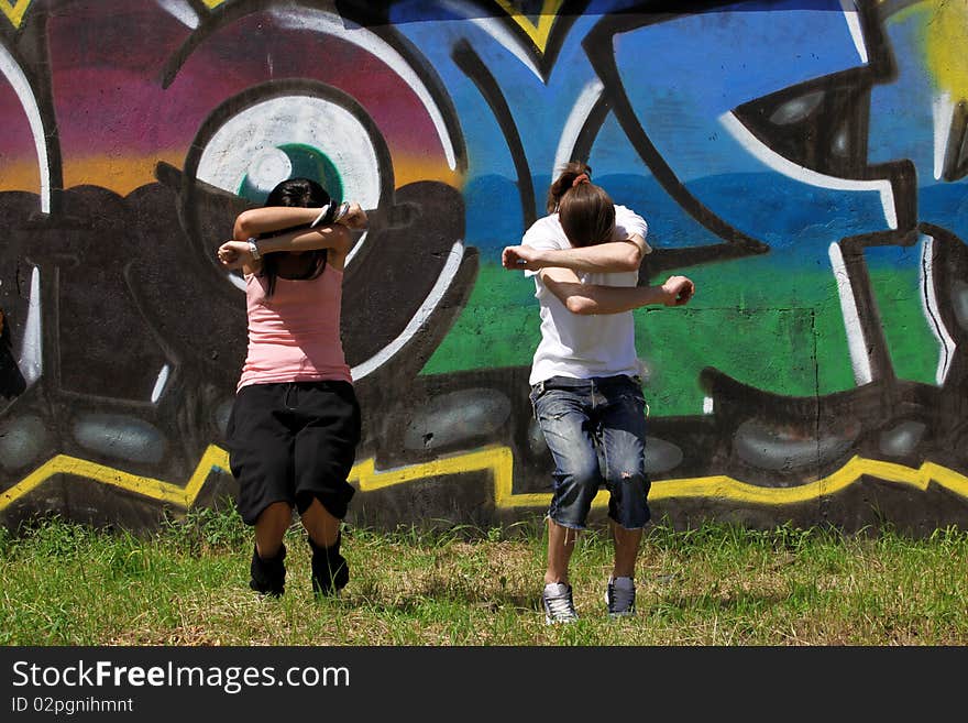 Woman modern dancers in city against graffiti wall