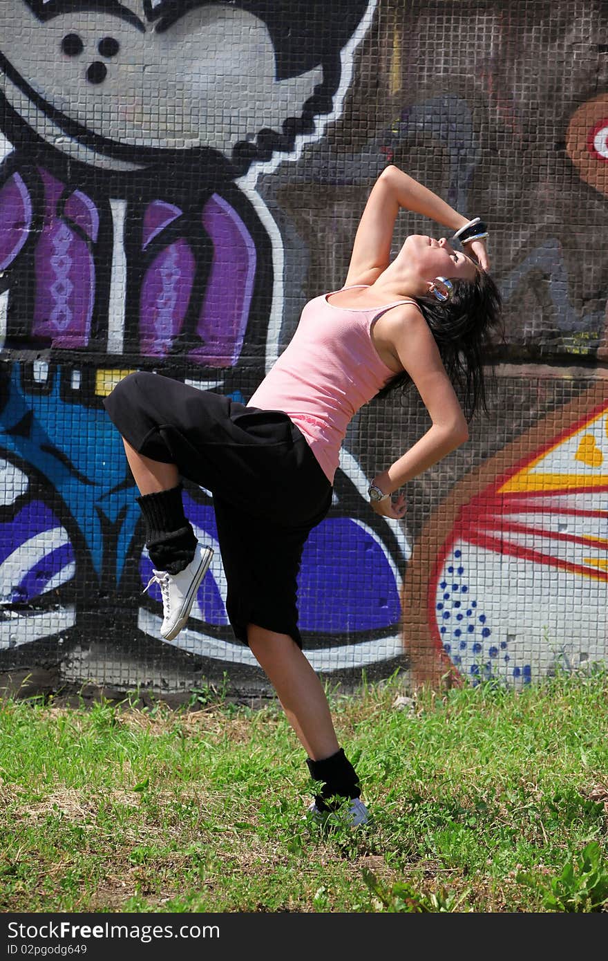 Woman modern ballet dancer in city against graffiti wall