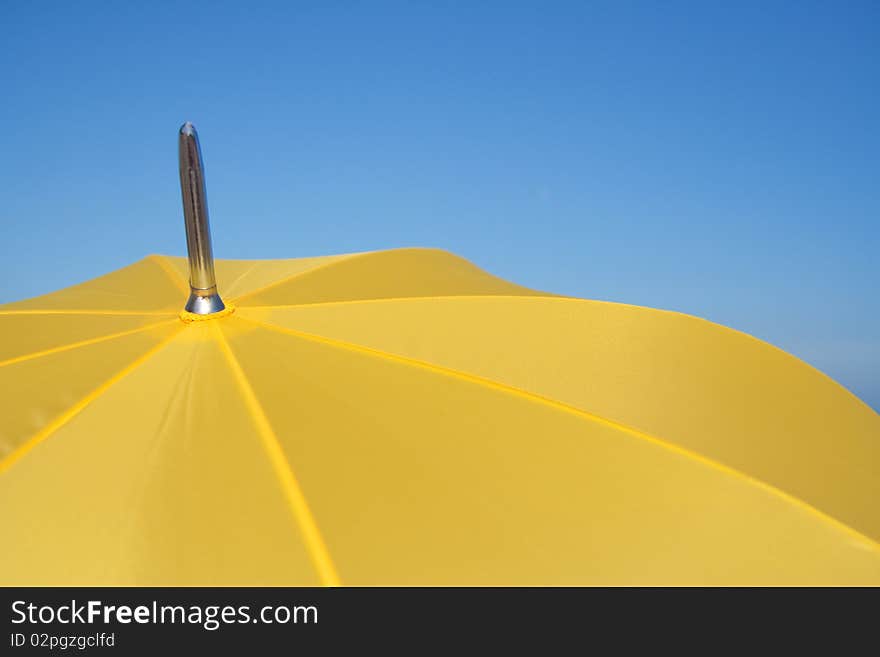 Opened parasol yellow against the blue sky. Opened parasol yellow against the blue sky