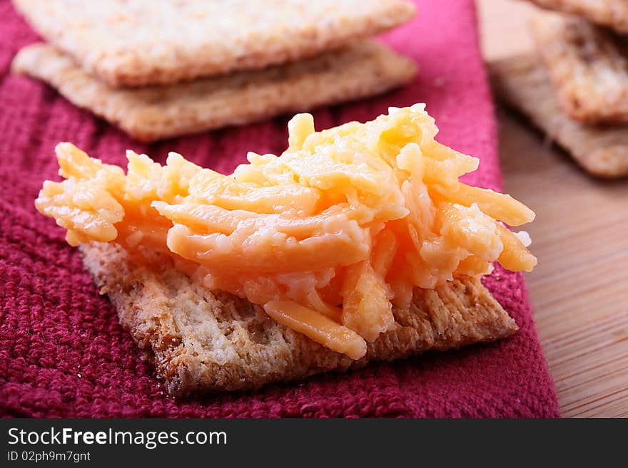 Wheat crackers on a kitchen board with grated garlick cheese. Wheat crackers on a kitchen board with grated garlick cheese.