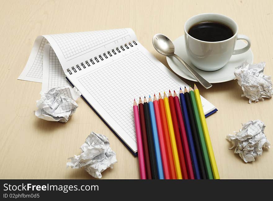 Coffee cup and spiral notebook and pen on the wooden table