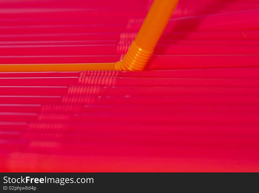 Many straws side by side, focus on the single orange straw