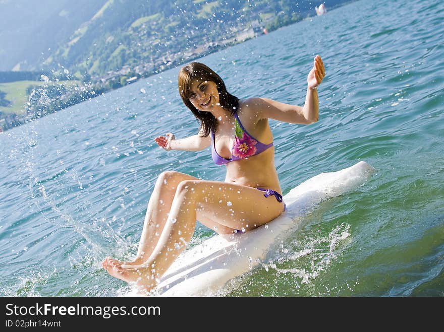 Girl having fun and relaxing on surfboard at the lake of Zell am See, Austria. Girl having fun and relaxing on surfboard at the lake of Zell am See, Austria