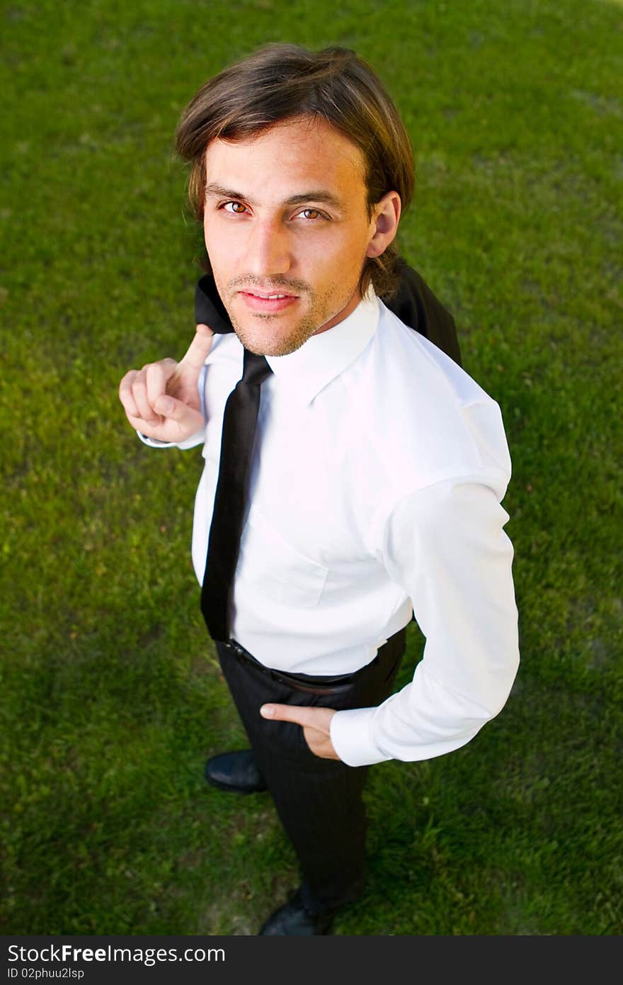 Young businessman over a green grassy background. Fresh smiling modell with longer hair. Young businessman over a green grassy background. Fresh smiling modell with longer hair.