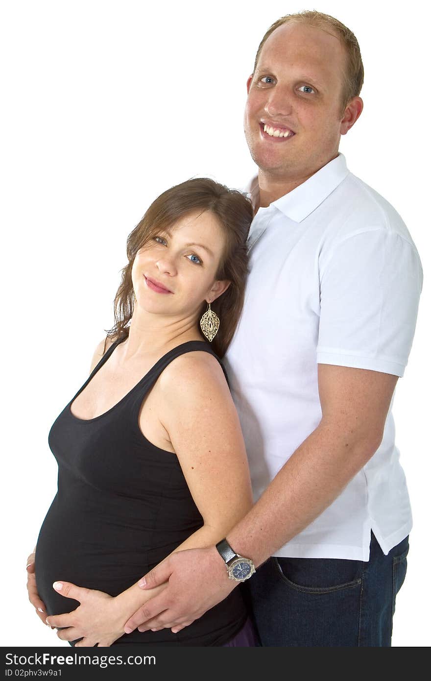 Young couple standing in studio setting isolated over white background. Woman is awaiting her first baby. Young couple standing in studio setting isolated over white background. Woman is awaiting her first baby.