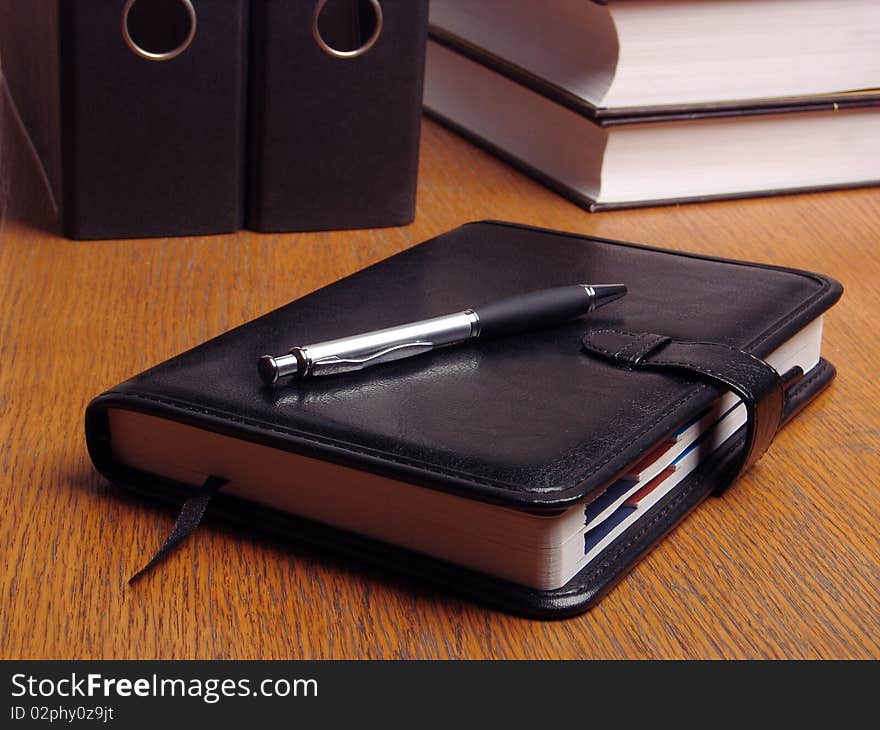 Black organizer on the office desk surrounded by documents and files