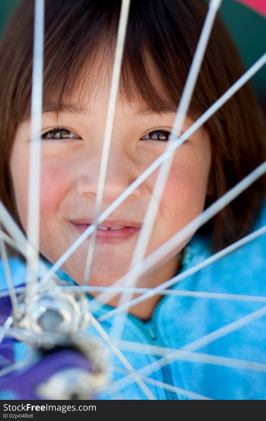 Girl behind a bike wheel.