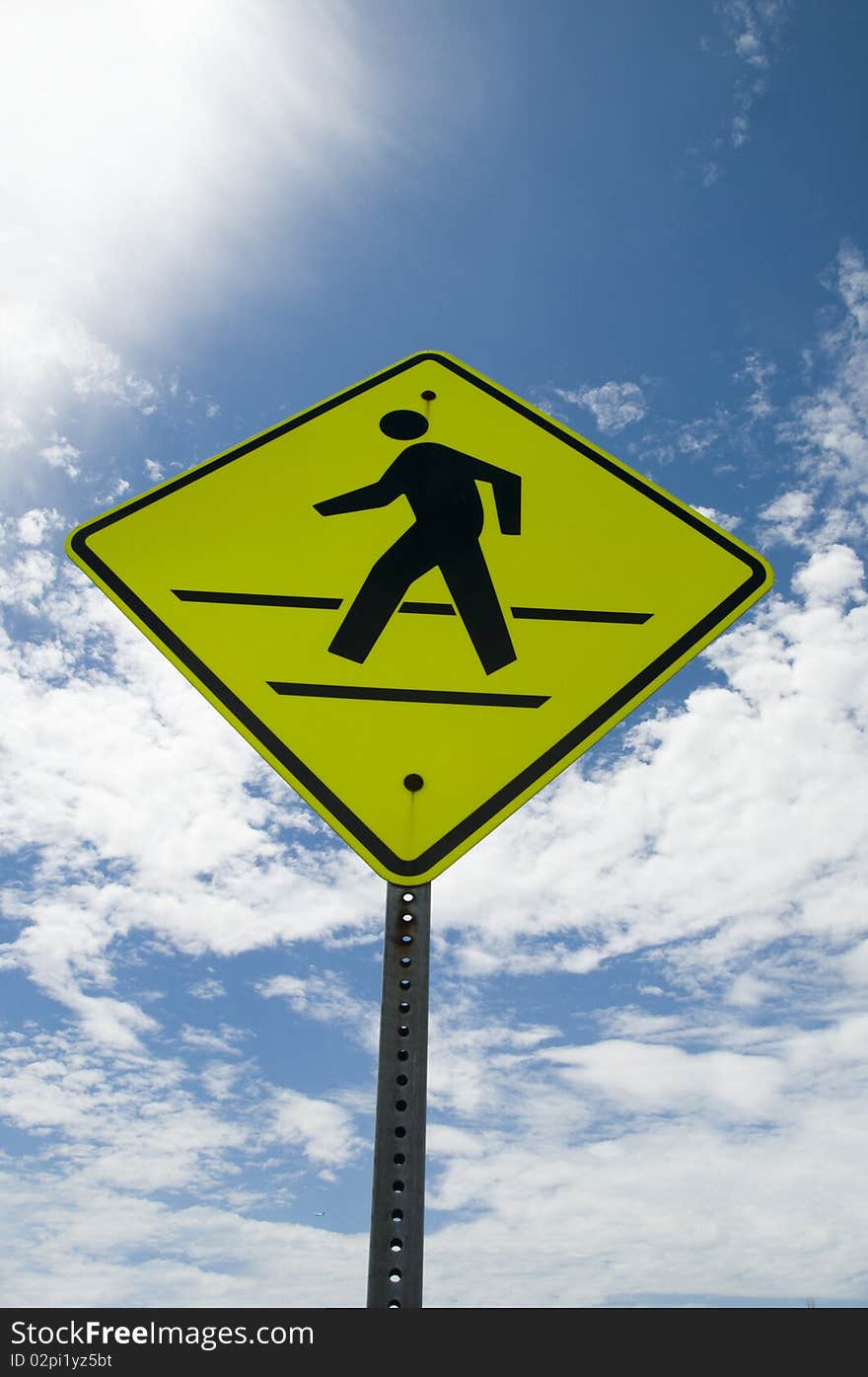 Walking traffic signage behing blue sky.