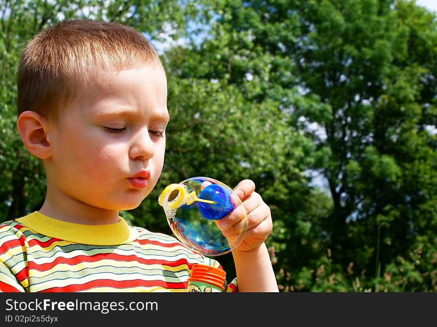 A child blowing bubble, background tree