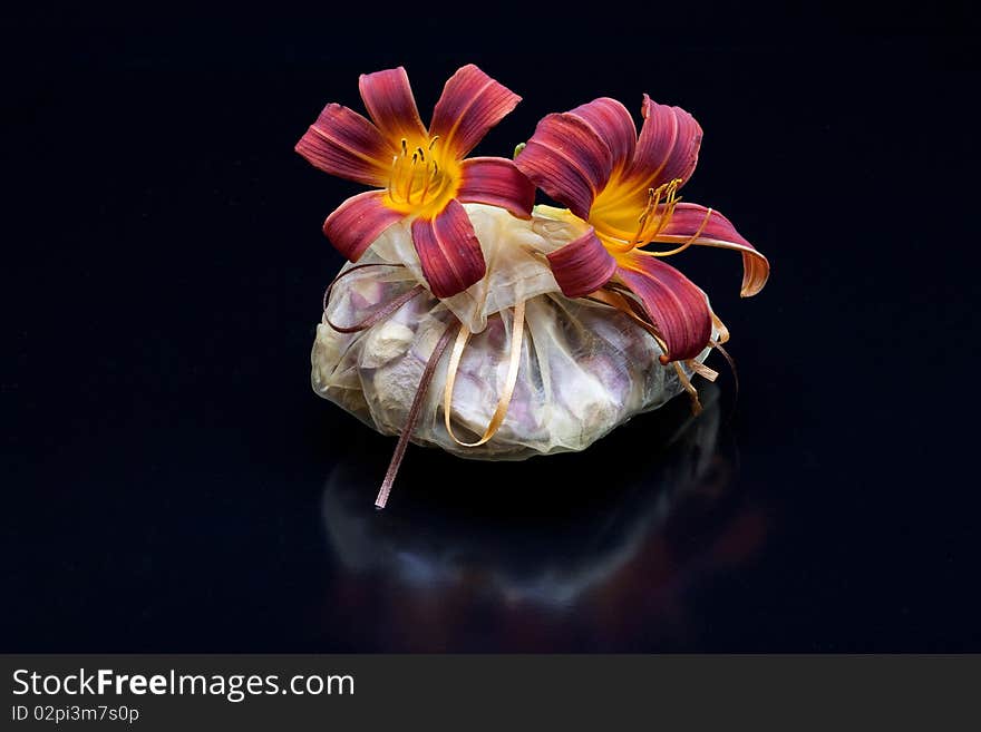 Red and yellow lilies on a bag of potpourri. Red and yellow lilies on a bag of potpourri.