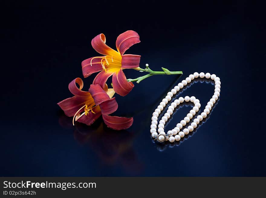 Red and yellow lilies and a pearl necklace.