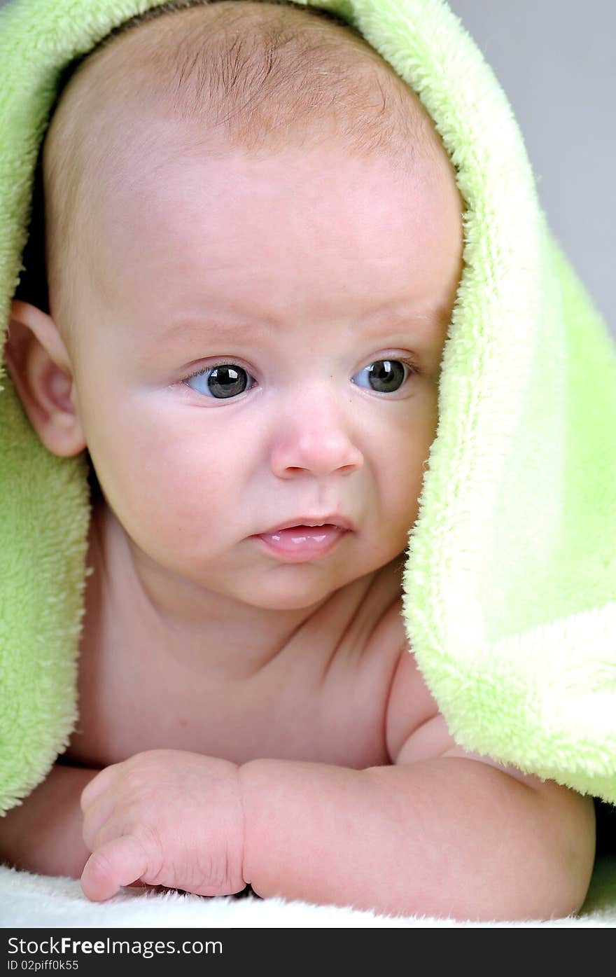 Cute little baby under green blanket