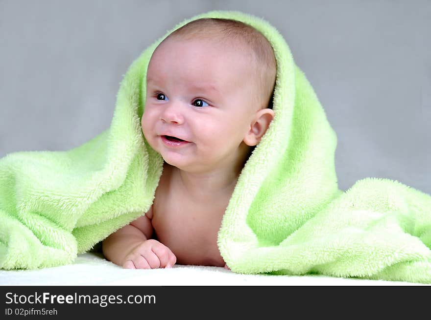 Cute little baby under green blanket